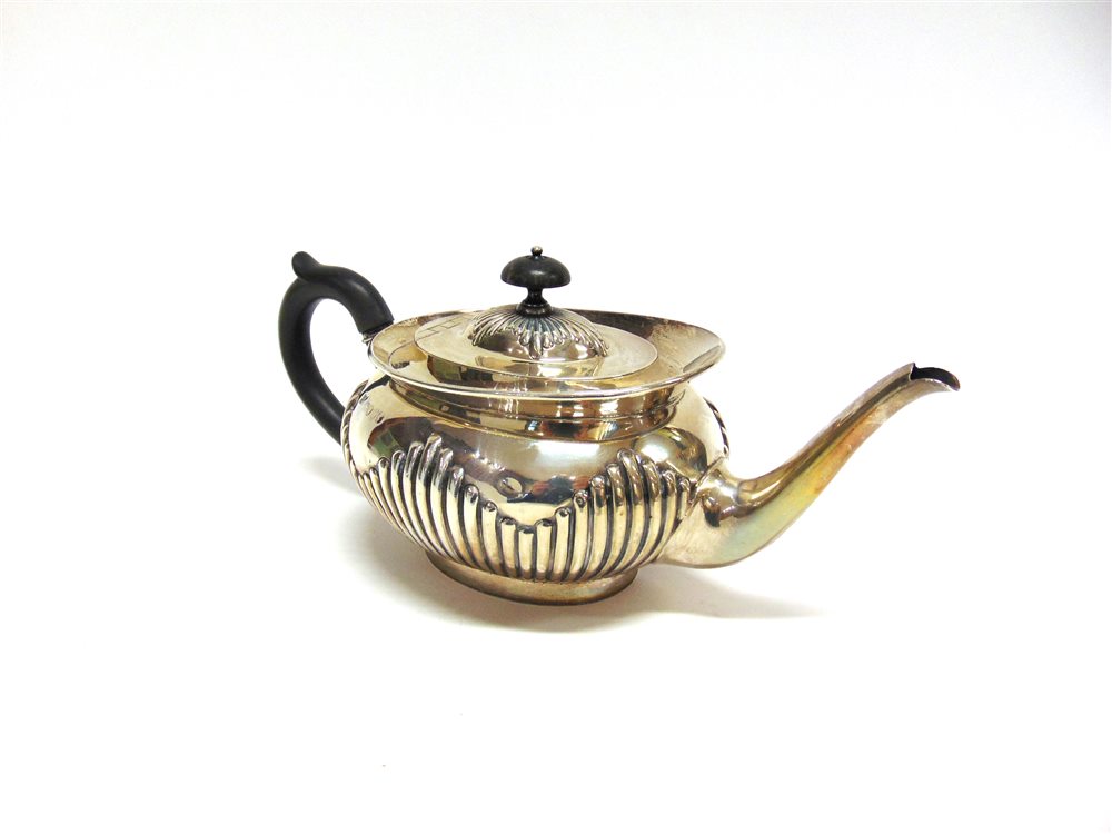 A LATE VICTORIAN SILVER TEAPOT by Edward Hutton, London 1888, of oval gadrooned form with a cape