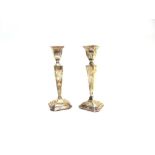 A PAIR OF SILVER CANDLESTICKS Birmingham 1915, the square loaded base rising to a tapering column,