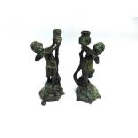 A PAIR OF PATINATED BRONZE FIGURAL CANDLESTICKS, modelled as winged cherubs, 28cm high