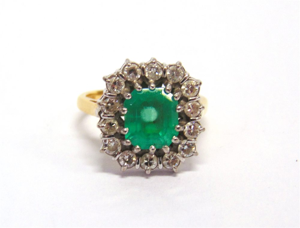 AN EMERALD AND DIAMOND CLUSTER RING stamped '18ct', the rectangular step cut stone, approximately