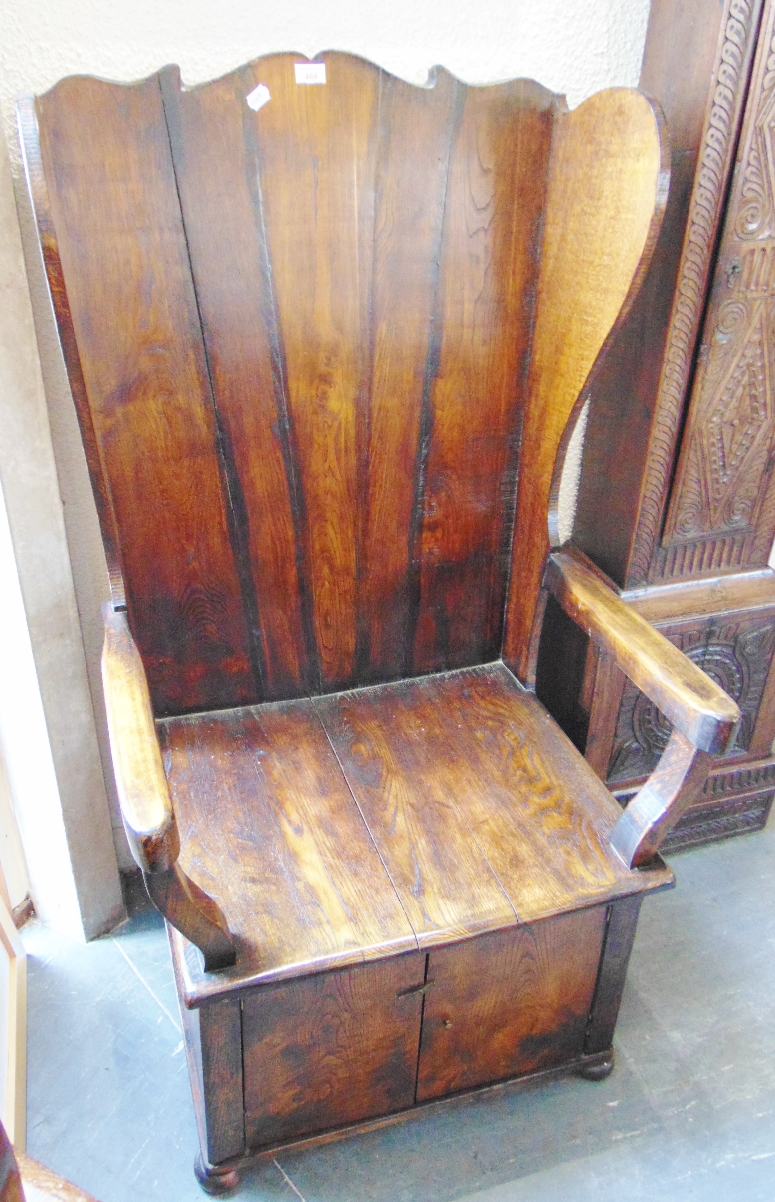 A 20TH CENTURY STANED OAK AND ELM LAMBING CHAIR, with shaped back and wing sides, solid seat over