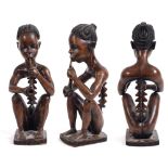 AN AFRICAN TRIBAL CARVED WOODEN FIGURE of rich patina, modelled as a seated male smoking a pipe, his