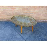 A BRASS TRAY TOP TABLE the heavy gauge brass top with embossed and chased decoration featuring