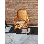 A CARVED WALNUT BERGERE ARMCHAIR with tapestry upholstered seat on cabriole front supports, 52cm