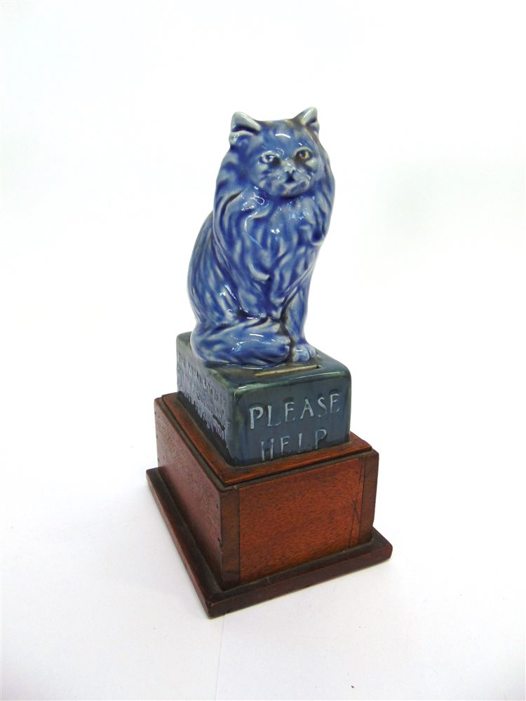 AN RSPCA CERAMIC CHARITY BOX, modelled as a seated cat on box inscribed 'PLEASE HELP THE ROYAL