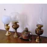 FOUR BRASS OIL LAMPS late 19th and early 20th century, three with glass chimneys and two with