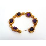 A 9 CARAT GOLD AMETHYST BRACELET the six oval cuts to textured and beaded mounts with cruciform