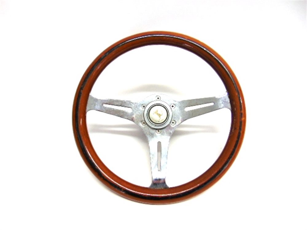 A SPORTS CAR STEERING WHEEL with a wooden rim, the central push-button horn with a Ferrari style