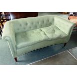 A BUTTON UPHOLSTERED TWO SEATER SOFA, with concave shaped front and scroll arms, on turned and