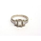 A THREE STONE STEP CUT DIAMOND RING stamped 'Plat 950', the central stone calculated as weighing