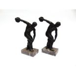 TWO BRONZED FIGURES OF DISCUS THROWERS on rectangular marble plinth bases, after the original by