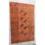 AN AFGHAN STYLE RUG with four octagonal guls within decorative border on a rust coloured ground,