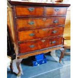 A CROSSBANDED WALNUT CHEST OF TWO SHORT AND THREE LONG DRAWERS, on associated stand with four carved