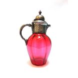 A LATE VICTORIAN CRANBERRY GLASS DECANTER with plated mounts and handle, 25cm high