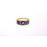 A LATE VICTORIAN SAPPHIRE THREE STONE RING stamped '18', the graduated round cuts with pairs of