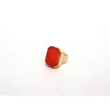 A CARNELIAN GOLD SIGNET RING unmarked, the large rectangular cut corner stone to a plain mount,