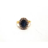 A SAPPHIRE & DIAMOND 18 CARAT GOLD CLUSTER RING the oval cut sapphire enclosed by twelve single