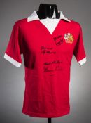 A red Manchester United retro jersey signed by the 'holy trinity' George Best,