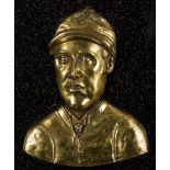 A brass relief plaque of the jockey Fred Archer, mounted on a backboard for wall mounting,