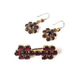 Yellow metal garnet brooch and earrings. Both set with circular cut garnets.