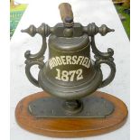 A ship’s bell complete with its ornate mount and hanger, as carried by the “S.S. HUDDERSFIELD”. A