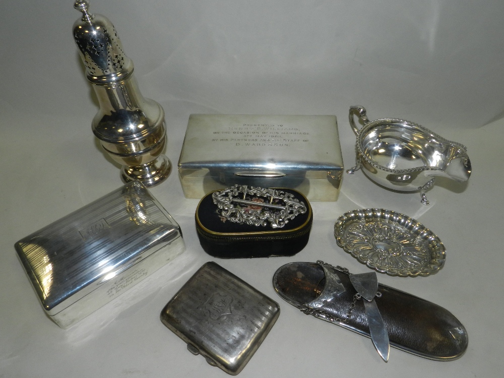 Two silver mounted cigarette boxes together with a silver cigarette case, a silver sauceboat,