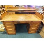 An early 20th century oak tambour front pedestal desk with frieze drawer and eight pedestal drawers.