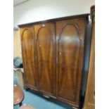 A Queen Anne style quarter veneered triple wardrobe with three ribbed doors on shell moulded