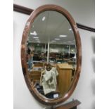 An arts & crafts style oval hammered copper wall mirror.