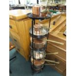 A six tier graduated black painted metal saucepan stand, six copper saucepans,