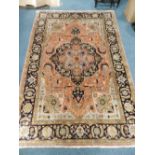 A Persian silk style carpet with central floral medallion and black foliate guard stripes.