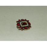 A foiled back garnet and seed pearl brooch