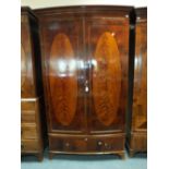 An Edwardian mahogany inlaid bowfront wardrobe having an ogee cornice above two doors and a single