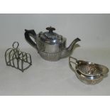A silver half reeded teapot together with a silver cream jug and a silver toast rack