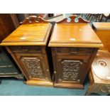 A pair of Edwardian walnut pot cupboards having carved panel doors