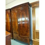 An Edwardian mahogany inlaid bowfront wardrobe having an ogee cornice above two doors and a single