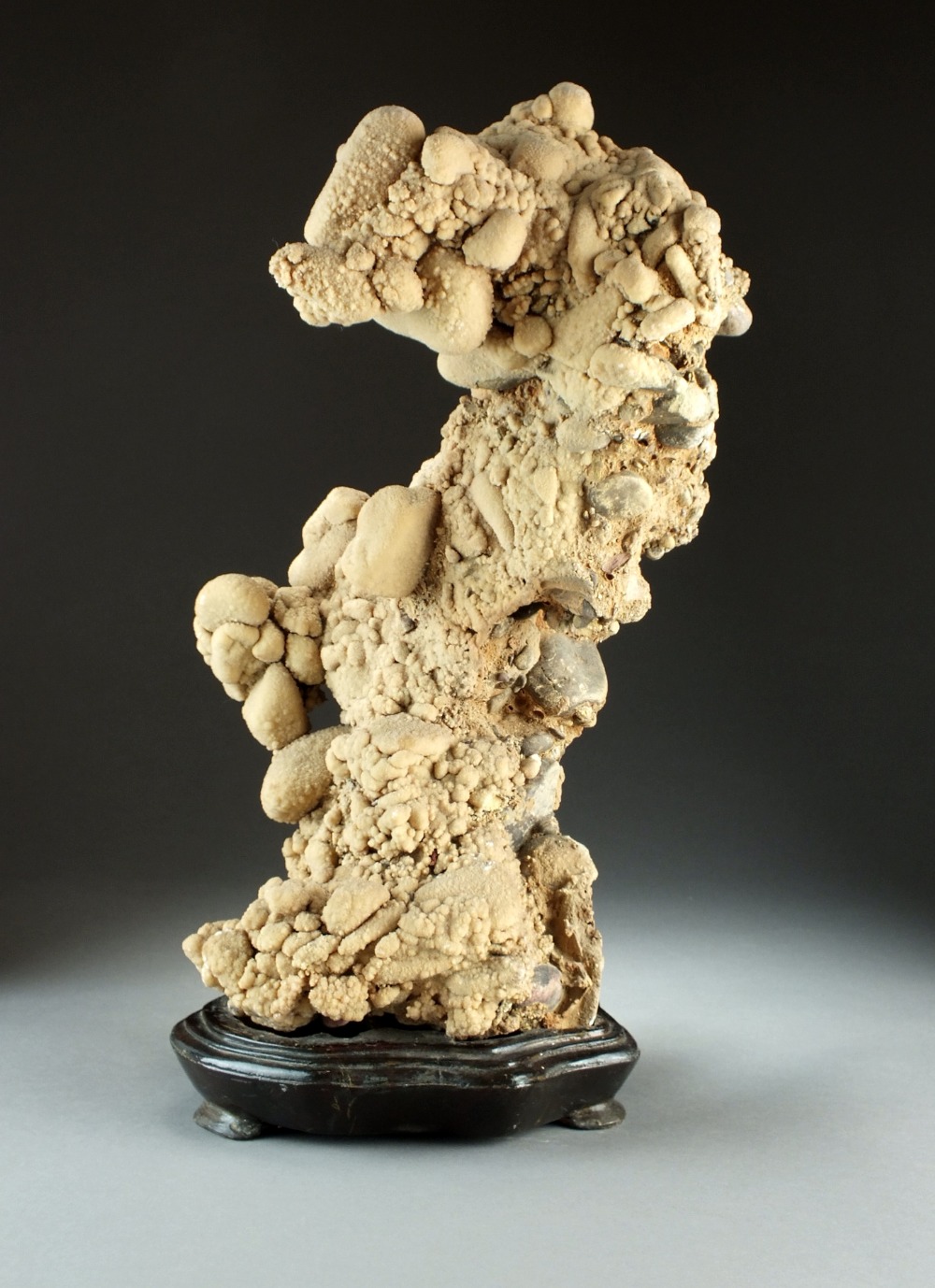 A large scholar's rock on stand, the pale orange stone probably aragonite with basalt inclusions,