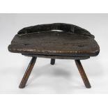 A 19th century Welsh primitive elm stool on three turned legs with single piece seat (evidence of