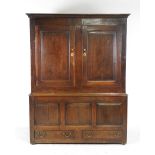 A mid 18th century oak livery cupboard the cavetto cornice over two rectangular fielded panel doors