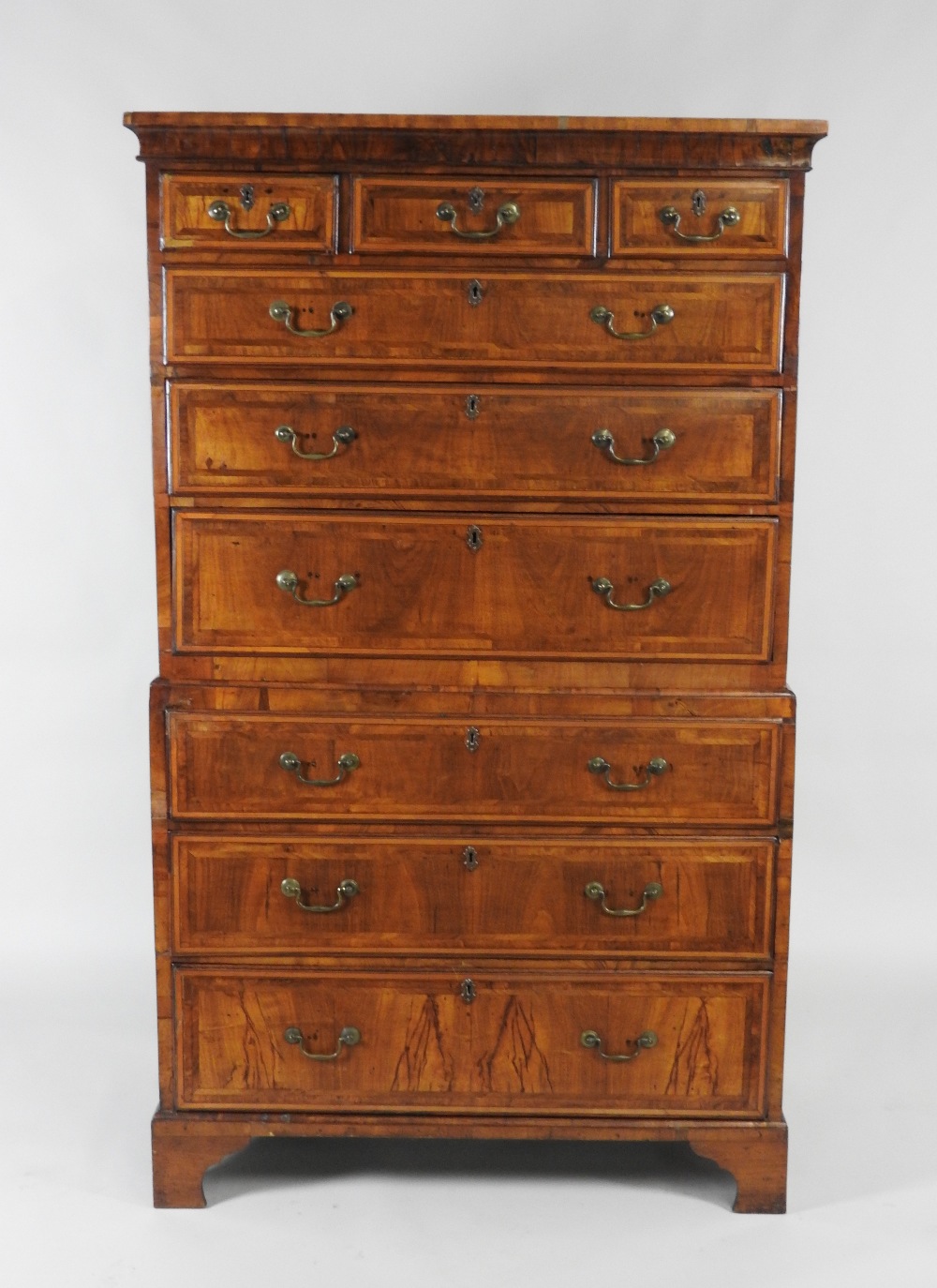 An early 18th century walnut crossbanded chest on chest the top section of three short over three