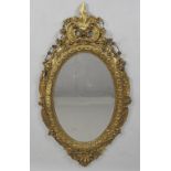 A mid Victorian gilt and gesso oval wall mirror with plain mirror plate the frame moulded with