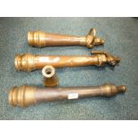 Three copper and brass fire hose nozzles and an additional end piece.