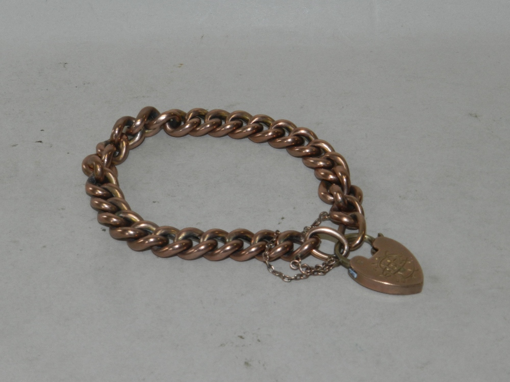 A yellow metal curb link bracelet with heart shaped padlock clasp, stamped 9ct.