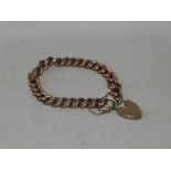 A yellow metal curb link bracelet with heart shaped padlock clasp, stamped 9ct.