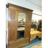 An early 20th century oak mirror door wardrobe, the cavetto cornice above a moulded frieze,