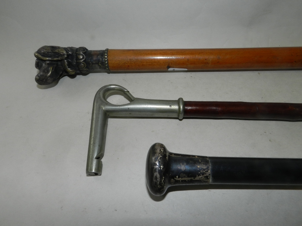 An ebonised walking cane with white metal handle together with a further walking cane with cast