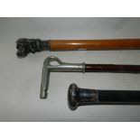 An ebonised walking cane with white metal handle together with a further walking cane with cast