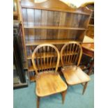 An early 20th century oak open bookcase together with a pair of Ercol kitchen chairs.
