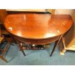 A 19th century inlaid and cross banded mahogany fold-over demi-lune table.