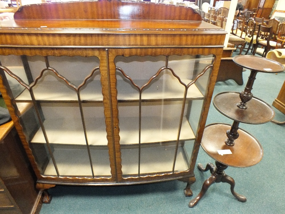 An early to mid 20th century bow front glazed display cabinet raised on ball and claw feet,